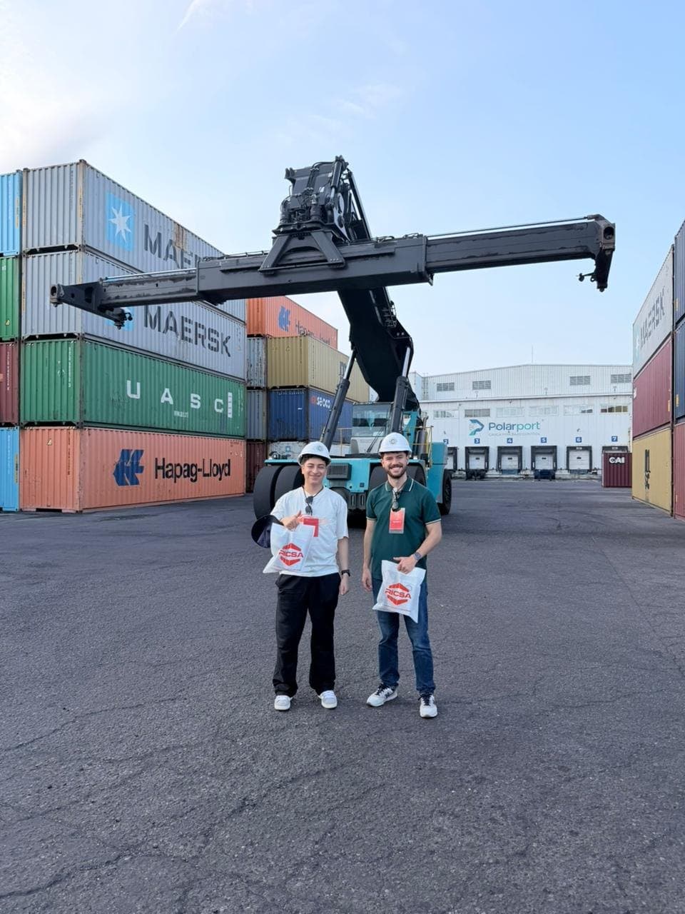 The team in front of a yard crane and Maersk and Hapag Lloyd containers